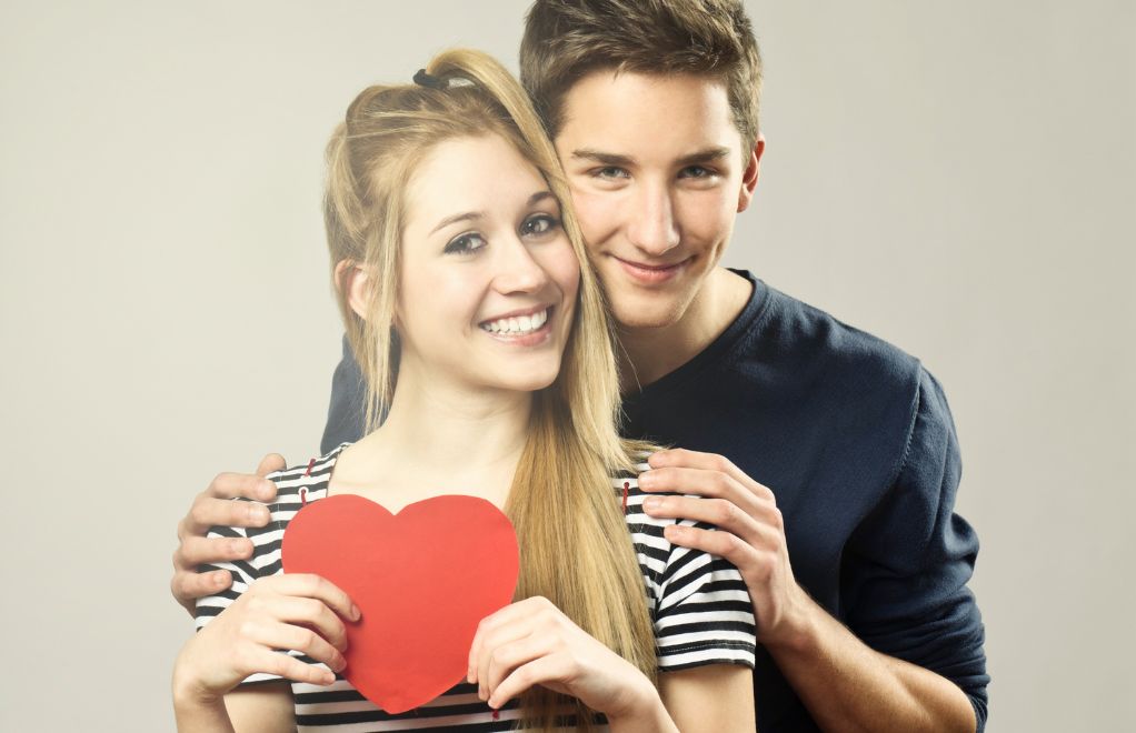 A couple standing together and holding a heart.