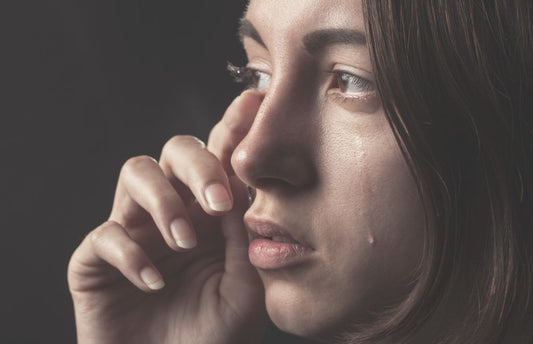 A woman wiping a tear from her eye.