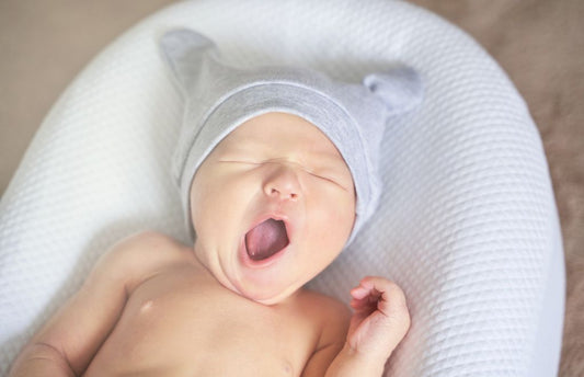 A baby that is yawning while lying down.